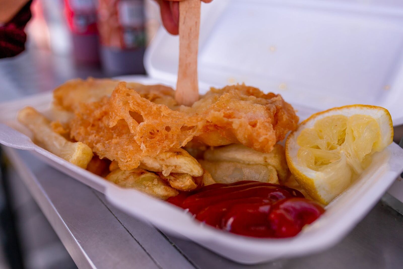Golden battered fish and chips with ketchup and a lemon wedge